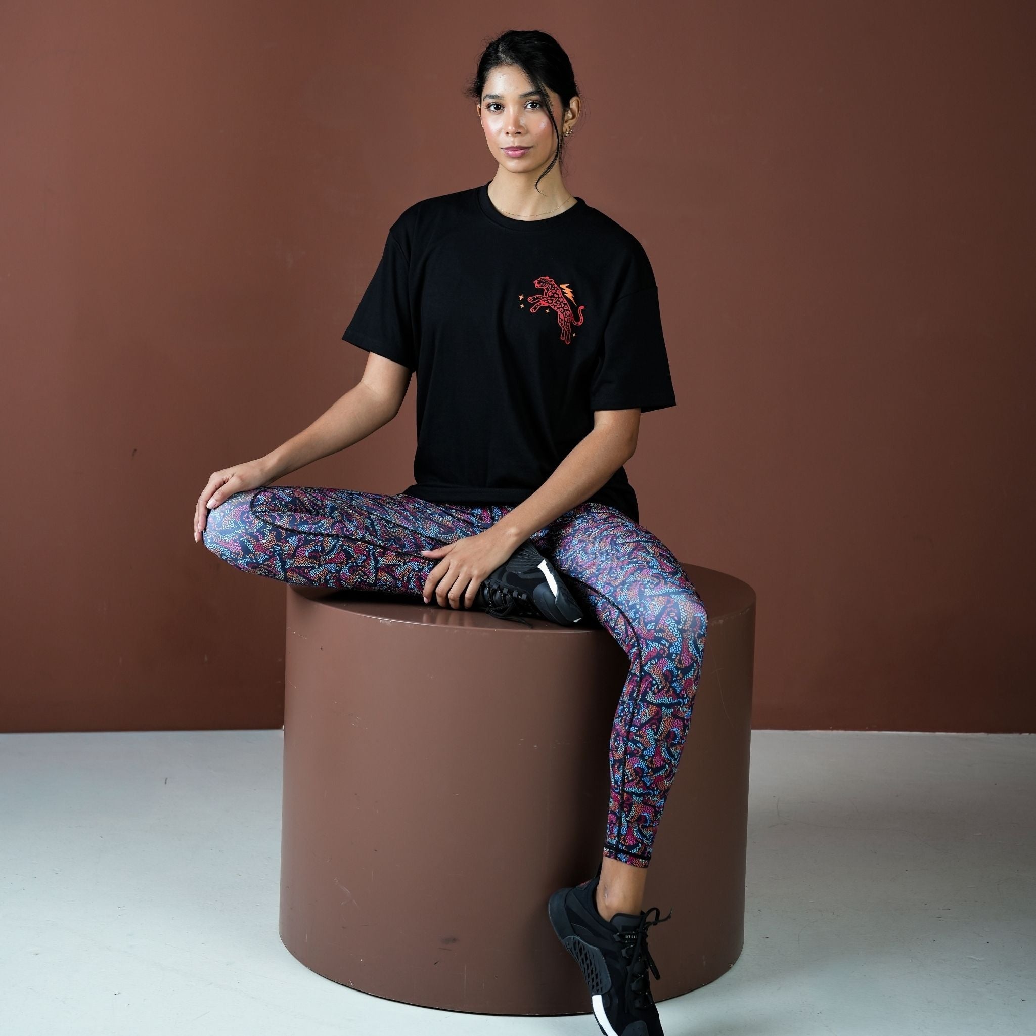 Person sitting on a brown cylindrical stool against a brown background