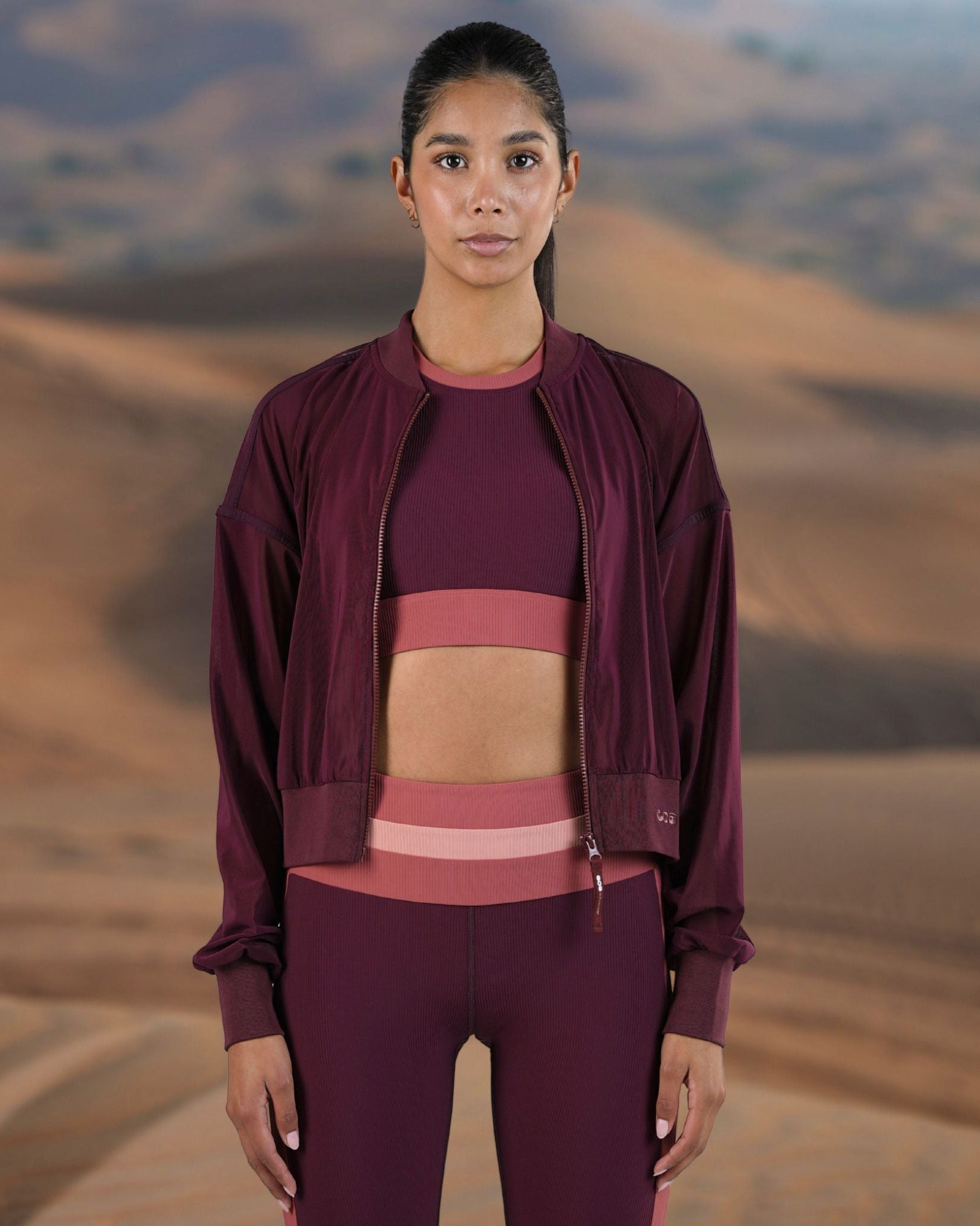 Woman in maroon athletic wear standing in a desert landscape