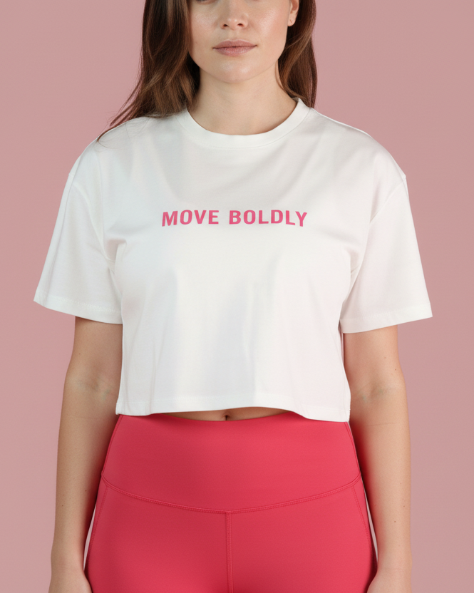 Woman wearing a white t-shirt with 'MOVE BOLDLY' text and red leggings on a pink background