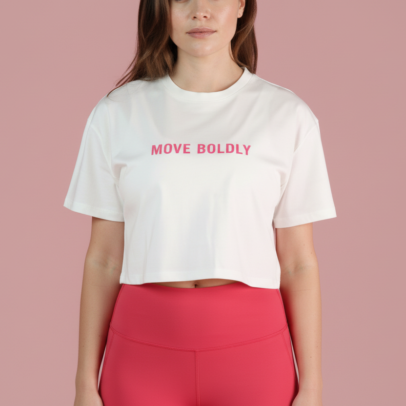 Woman wearing a white t-shirt with 'MOVE BOLDLY' text and red leggings on a pink background