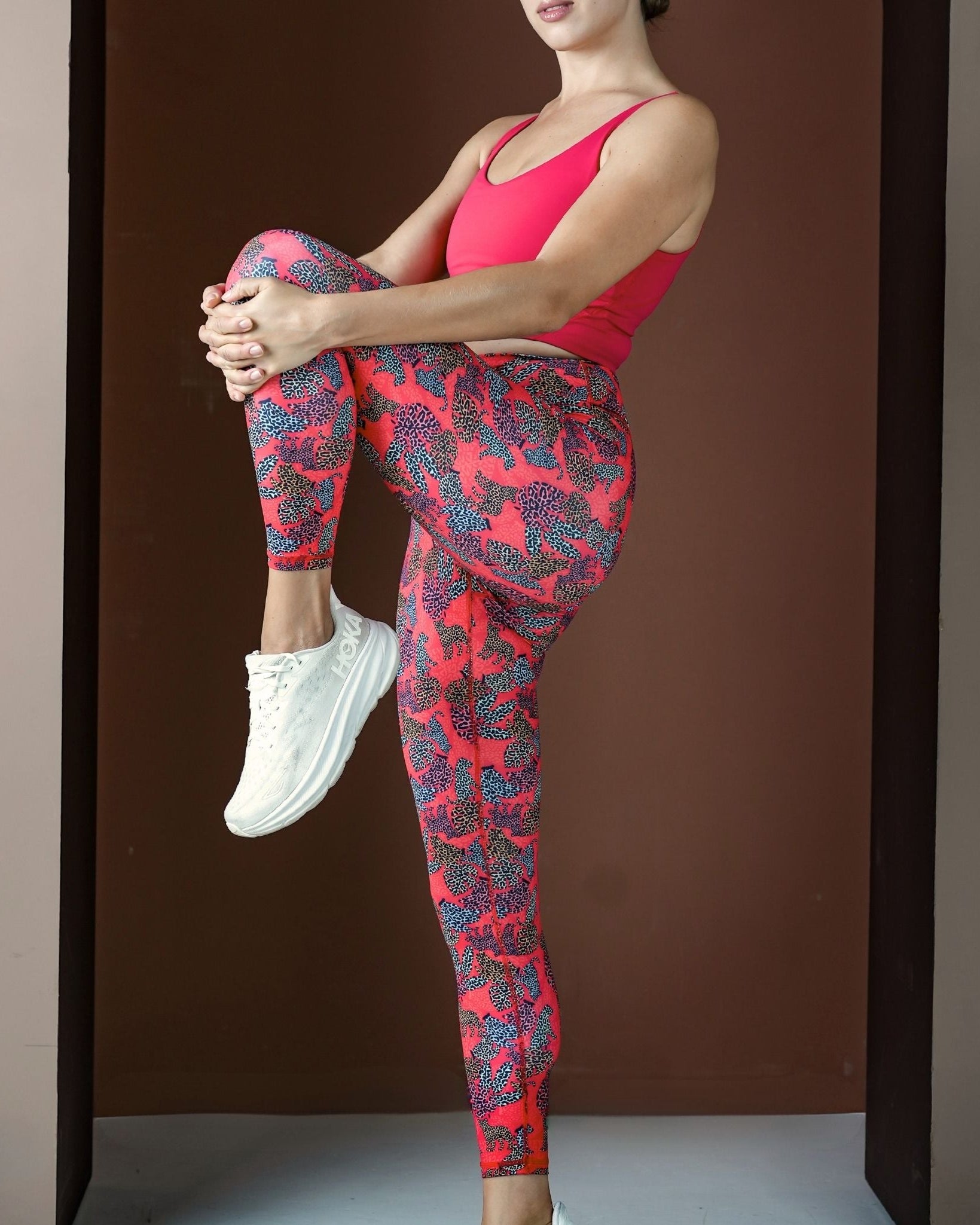 Person wearing red and pink patterned leggings with a plain background