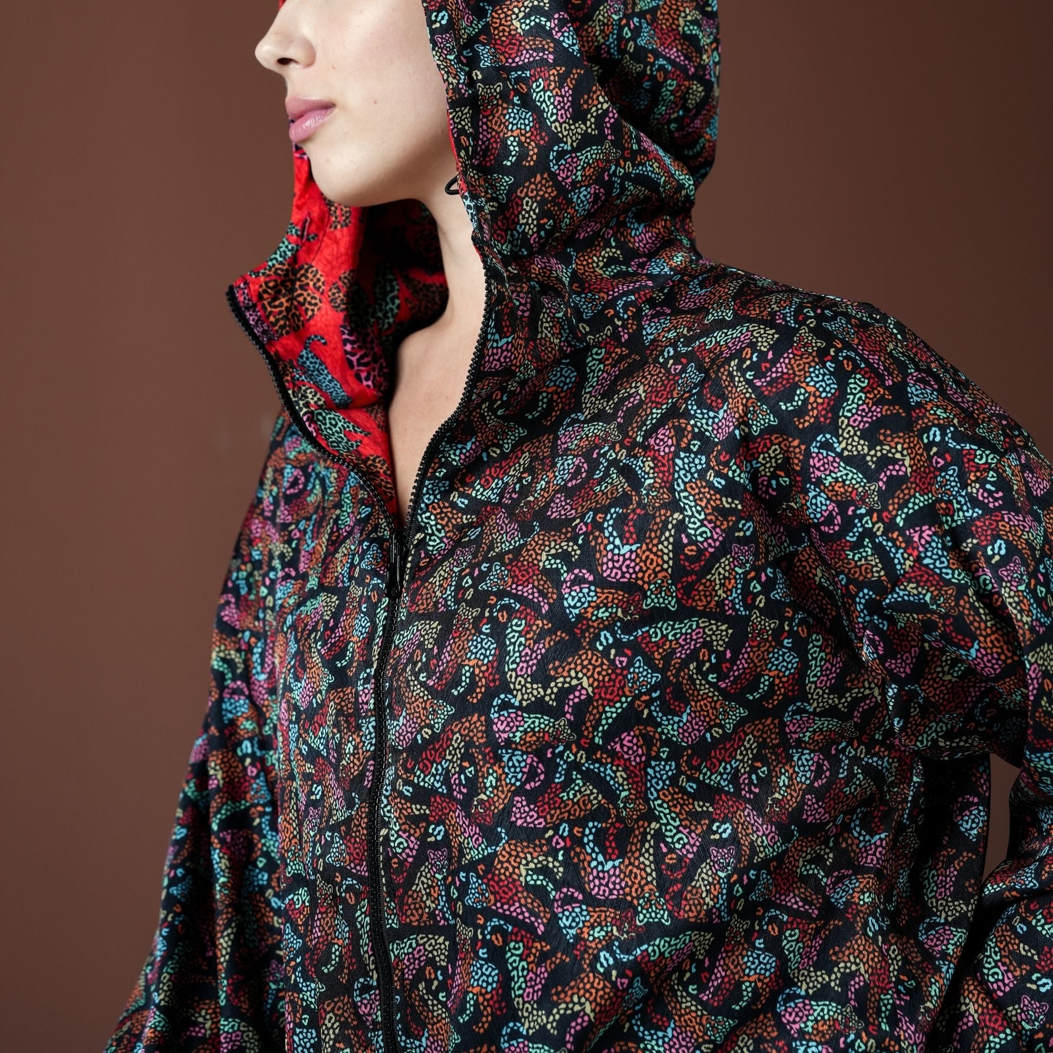 Person wearing a colorful patterned jacket with a hood on a brown background