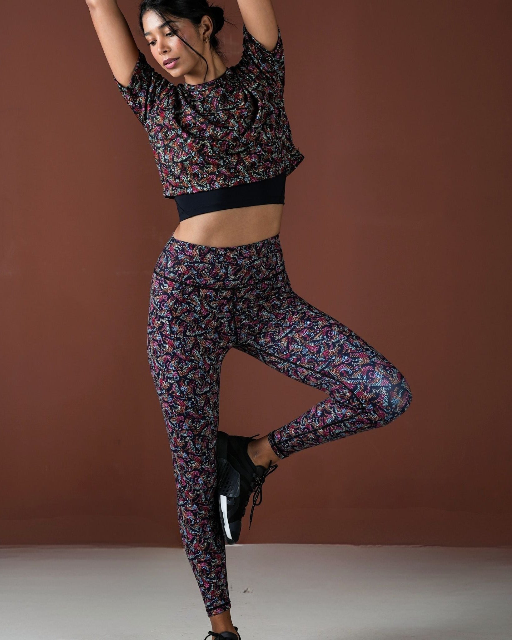 Woman in patterned athletic outfit posing against a brown background