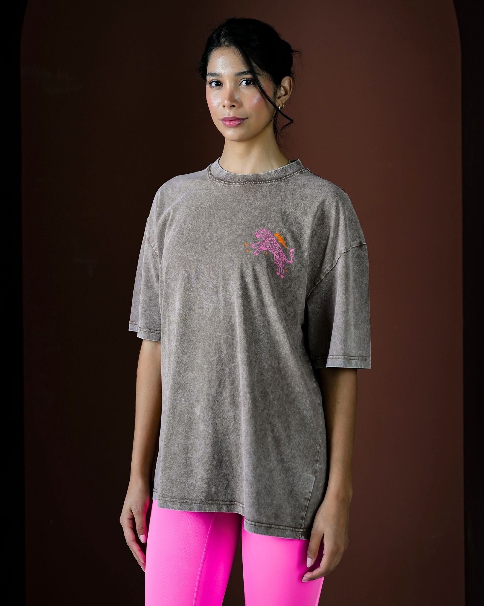 Woman wearing a gray t-shirt with a colorful design on a dark background