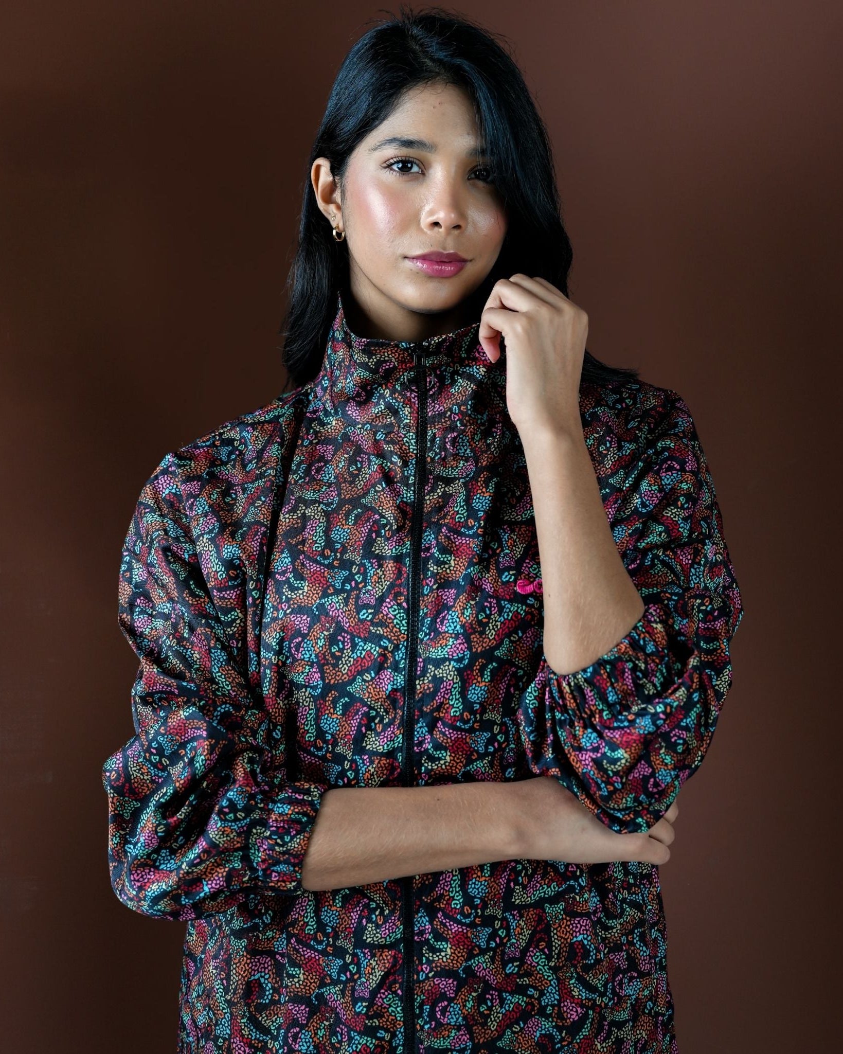 Woman wearing a colorful patterned outfit against a brown background