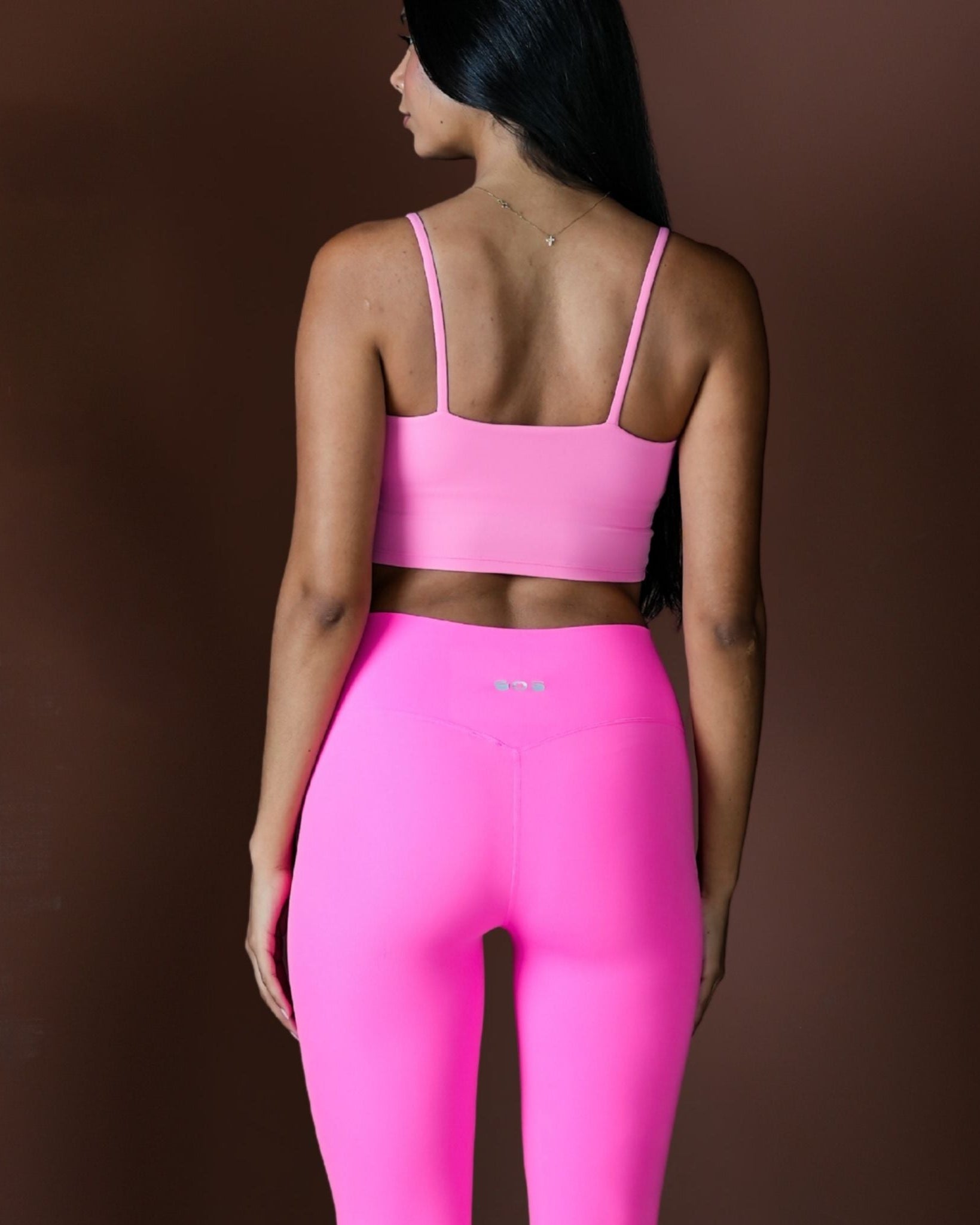 Person wearing a pink sports bra and leggings on a brown background