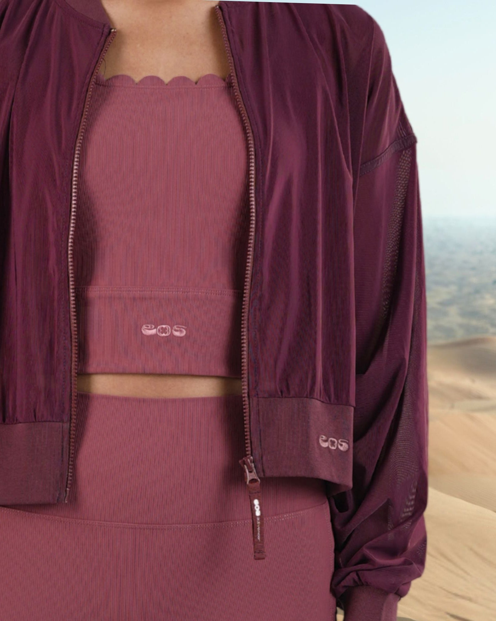 Maroon outfit with a jacket over a pink top and skirt, set against a desert landscape.