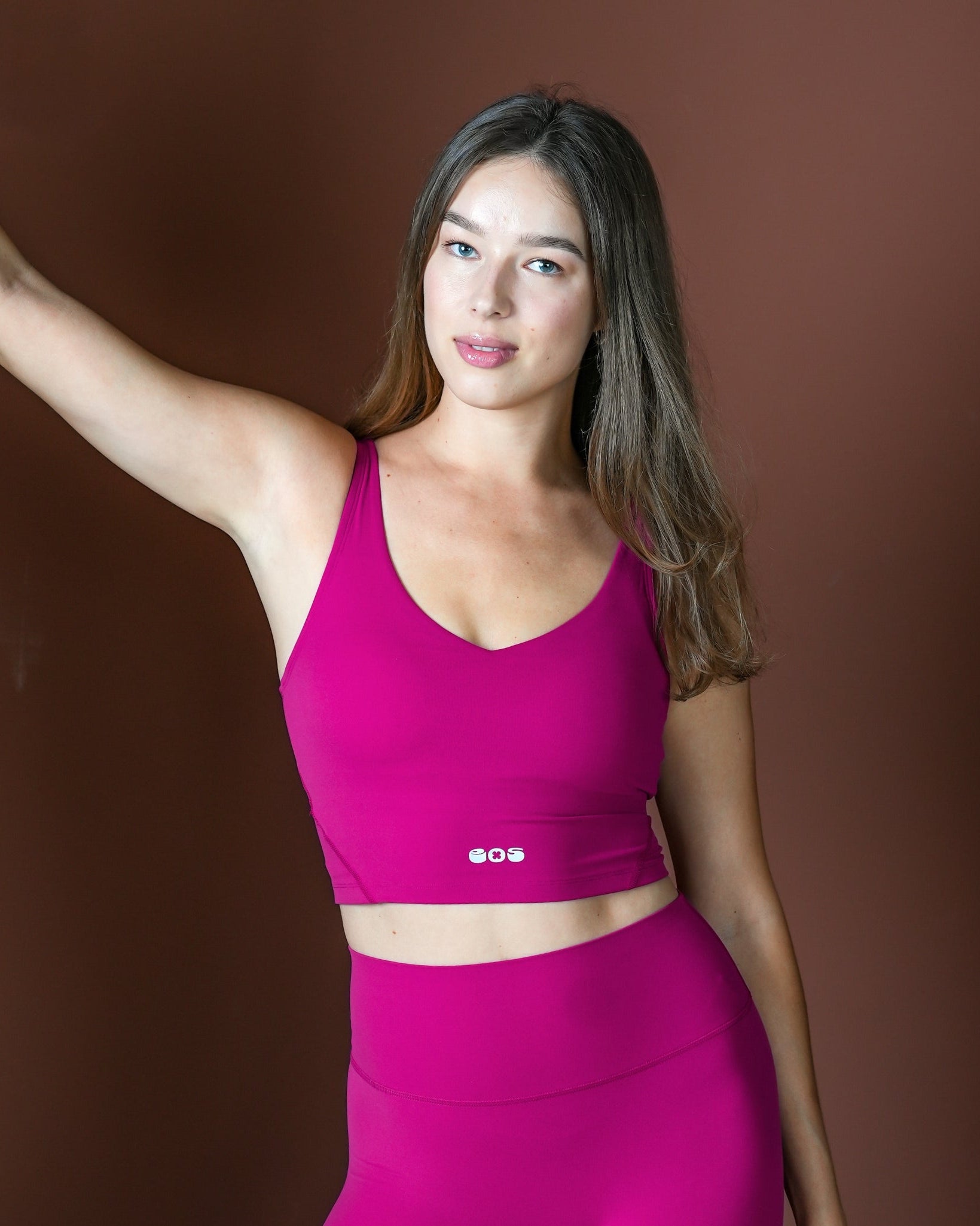 Woman wearing a pink sports bra and leggings against a brown background