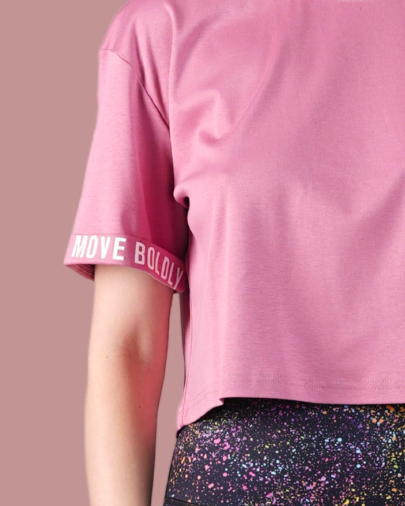 Pink t-shirt with rolled-up sleeves and colorful pants on a beige background