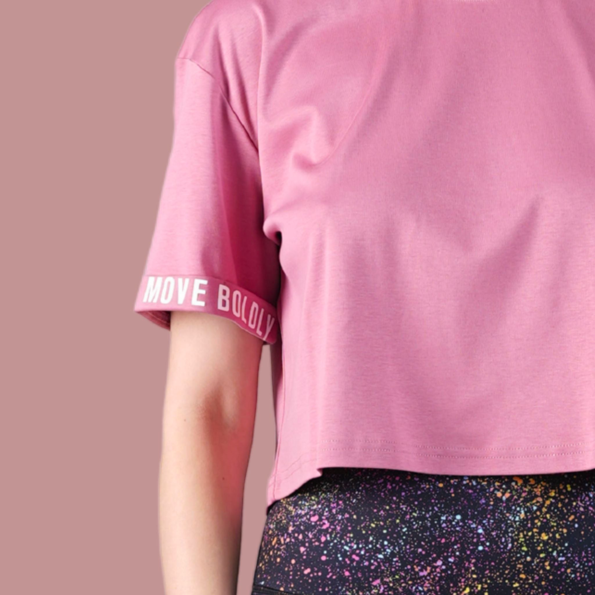 Pink t-shirt with rolled-up sleeves and colorful pants on a beige background