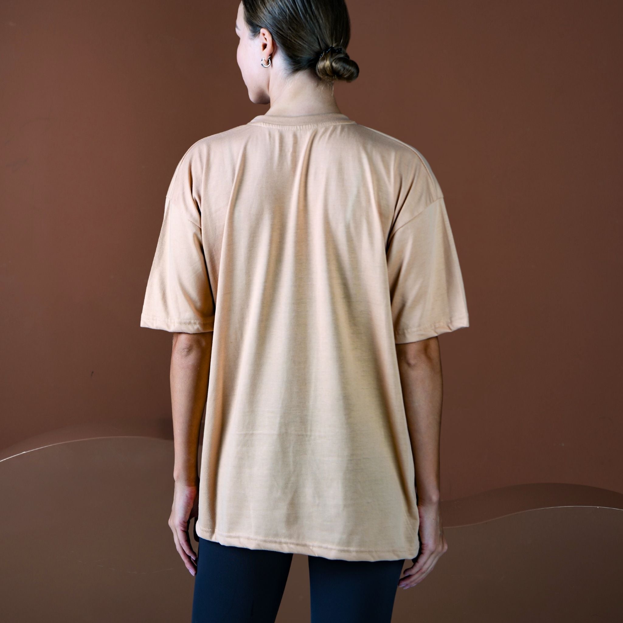 Person wearing a beige t-shirt against a brown background