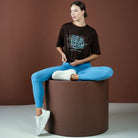 Person sitting on a brown cylindrical stool against a brown background
