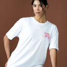 Woman wearing a white t-shirt with a pink and orange graphic on a brown background