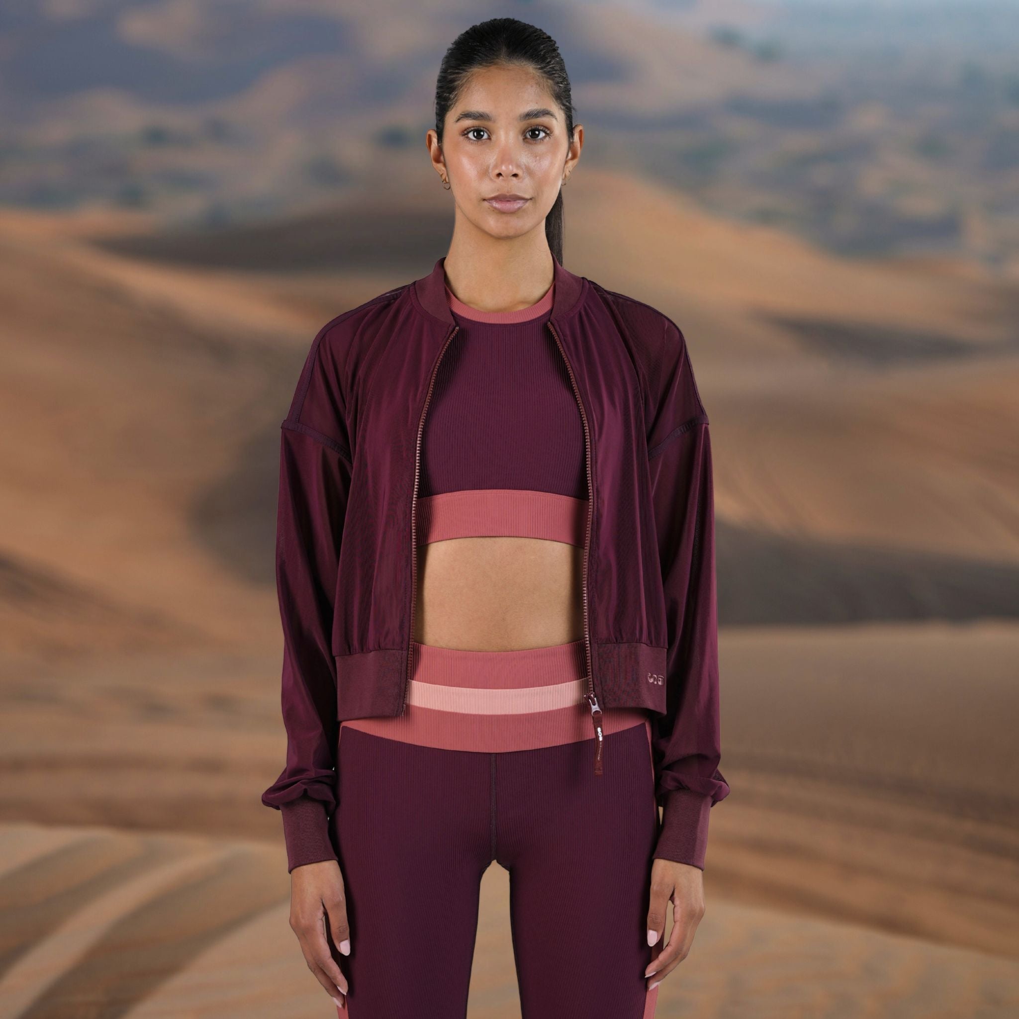 Woman in maroon athletic wear standing in a desert landscape