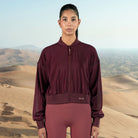 Person wearing a maroon tracksuit with a desert landscape in the background
