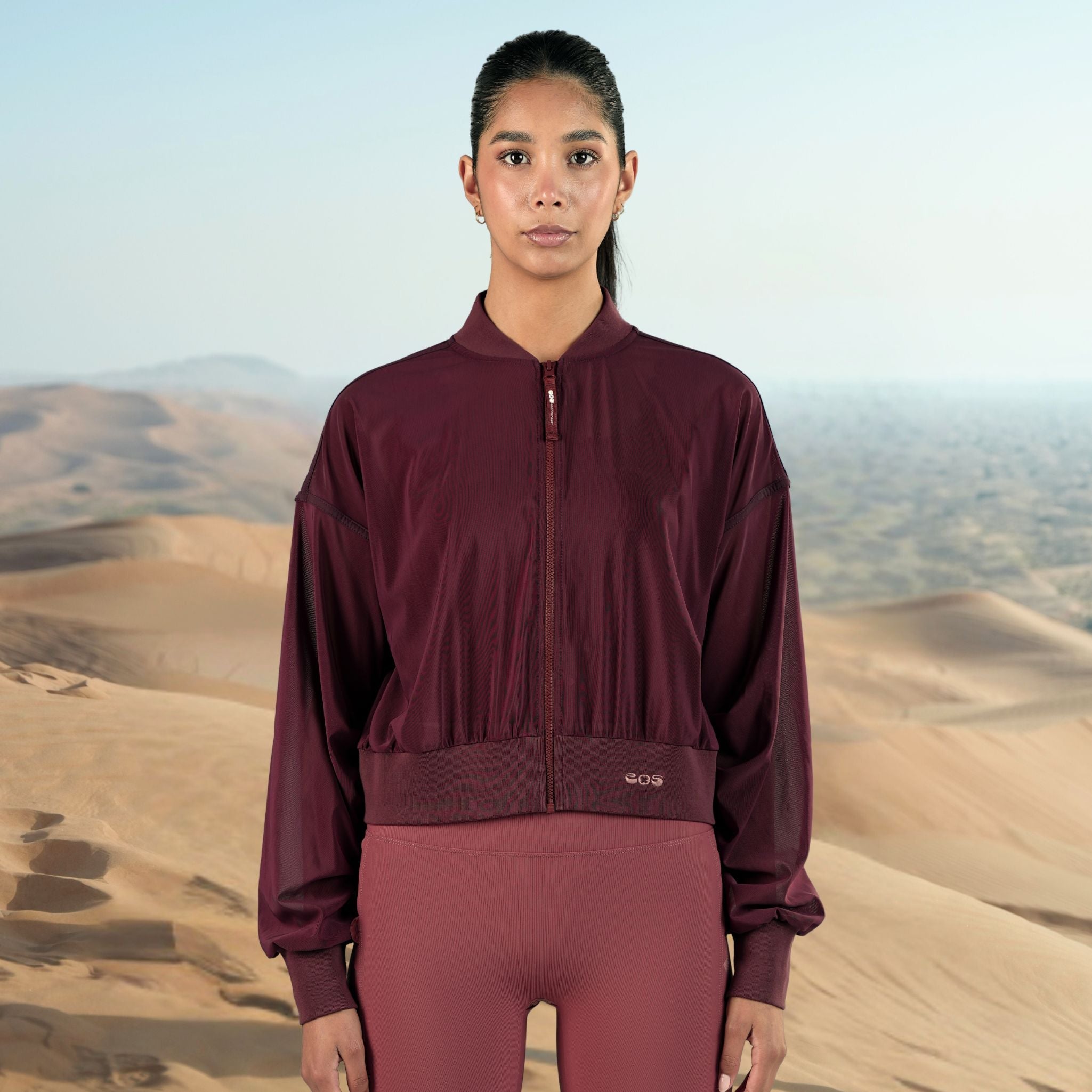 Person wearing a maroon tracksuit with a desert landscape in the background