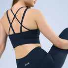 Person wearing a navy sports bra and leggings with a visible brand logo on a light blue background