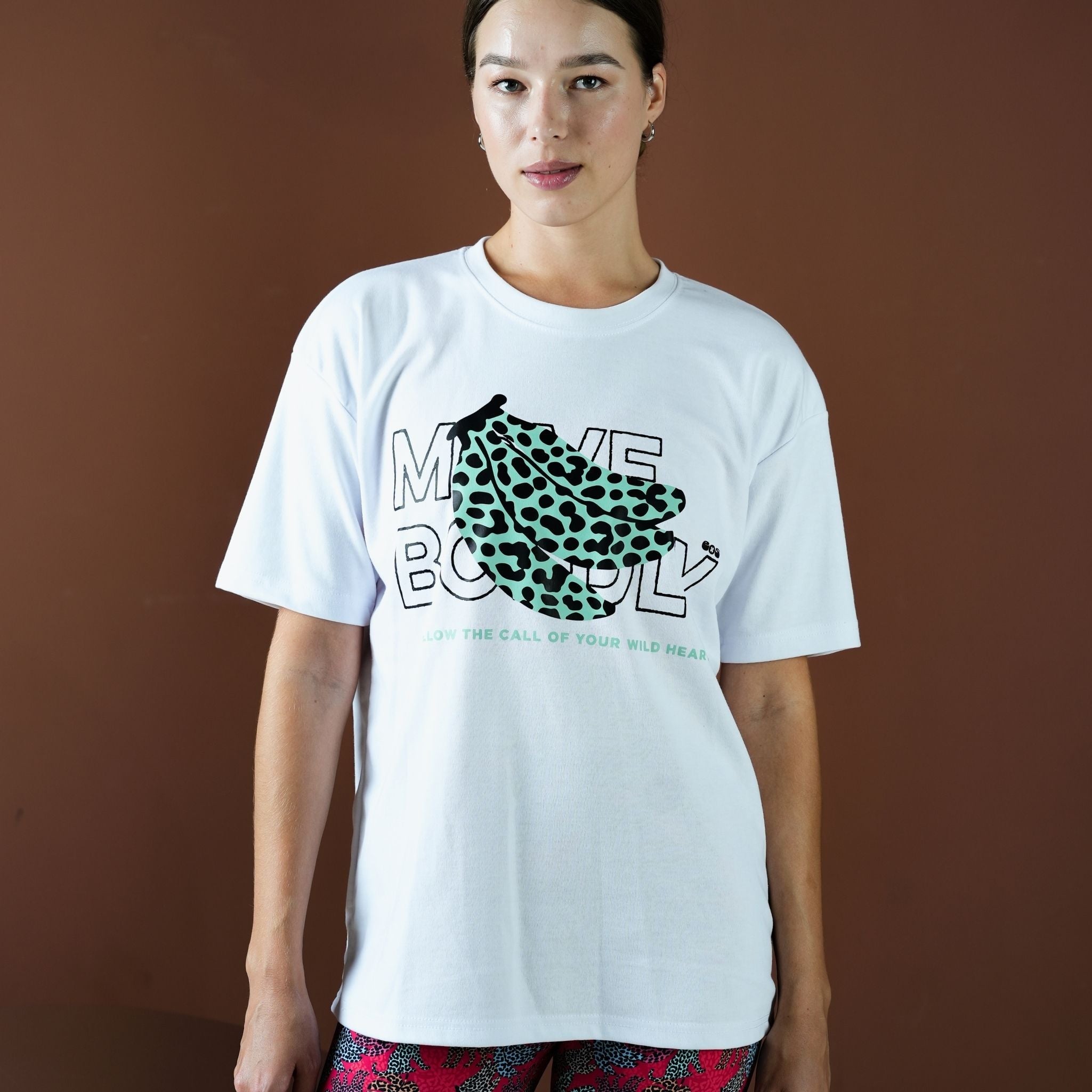 Person wearing a white t-shirt with a graphic design and text against a brown background