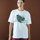 Person wearing a white t-shirt with a graphic design and text against a brown background