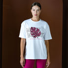 Person wearing a white t-shirt with a pink and black graphic design on a brown background