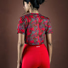 Person wearing a red patterned top and red leggings on a brown background