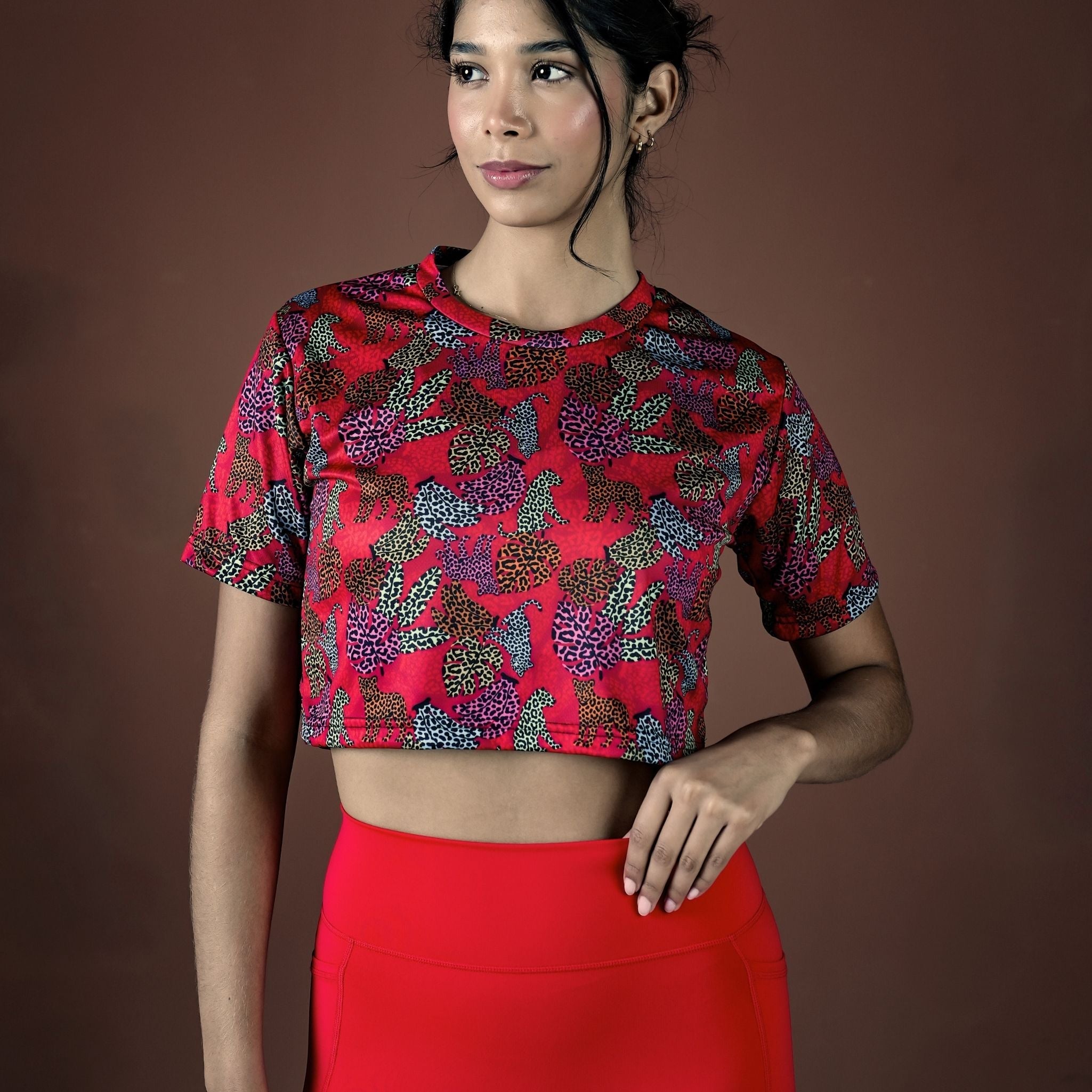 Woman wearing a red patterned top and red skirt against a brown background