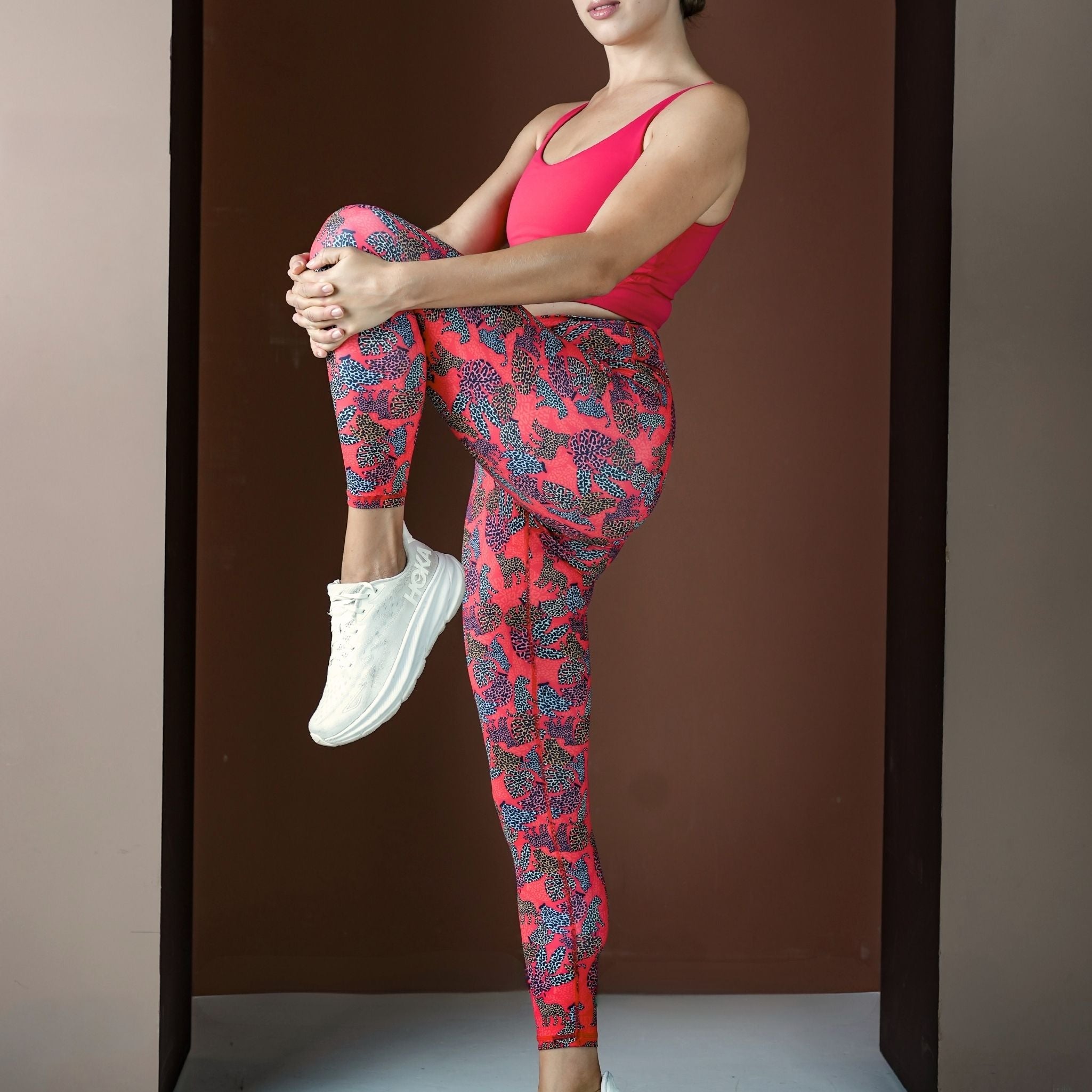 Person wearing red and pink patterned leggings with a plain background