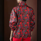 Person wearing a red patterned jacket against a brown background