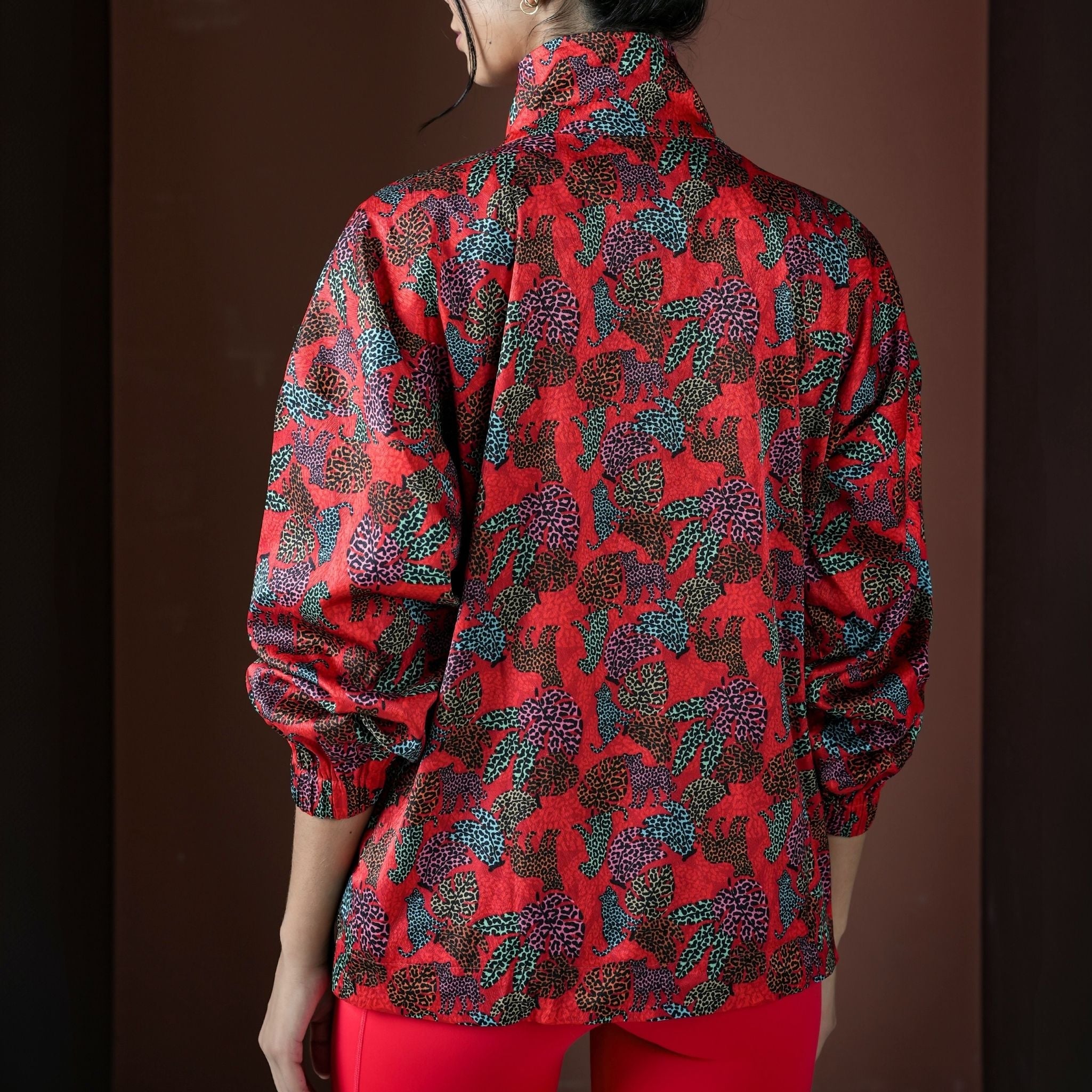 Person wearing a red patterned jacket against a brown background