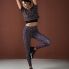 Woman in patterned athletic outfit posing against a brown background