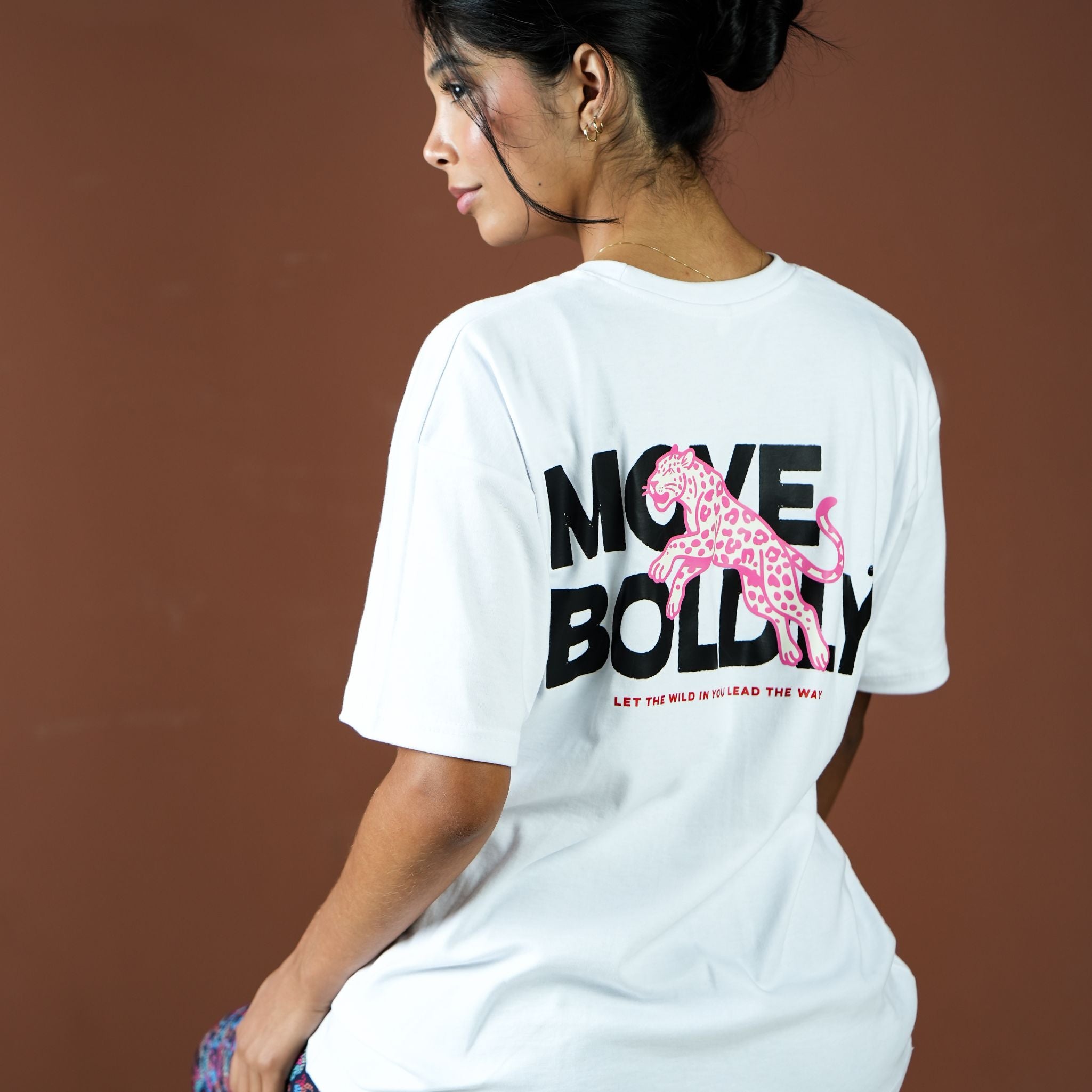 Person wearing a white t-shirt with 'Move Boldly' graphic design on the back.