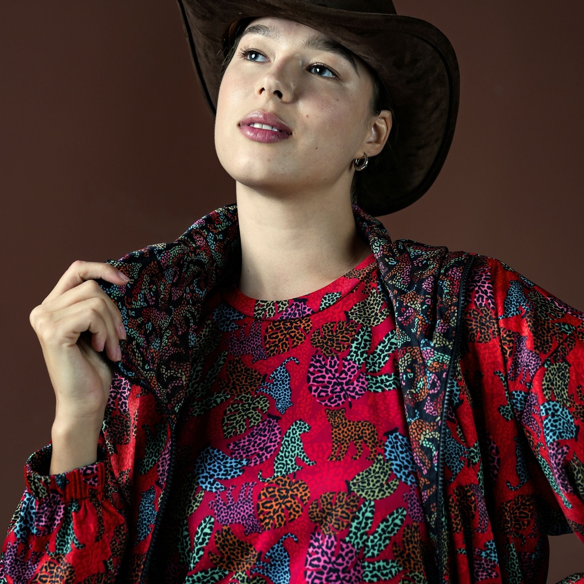 Woman wearing a colorful patterned jacket over a red shirt with a brown background