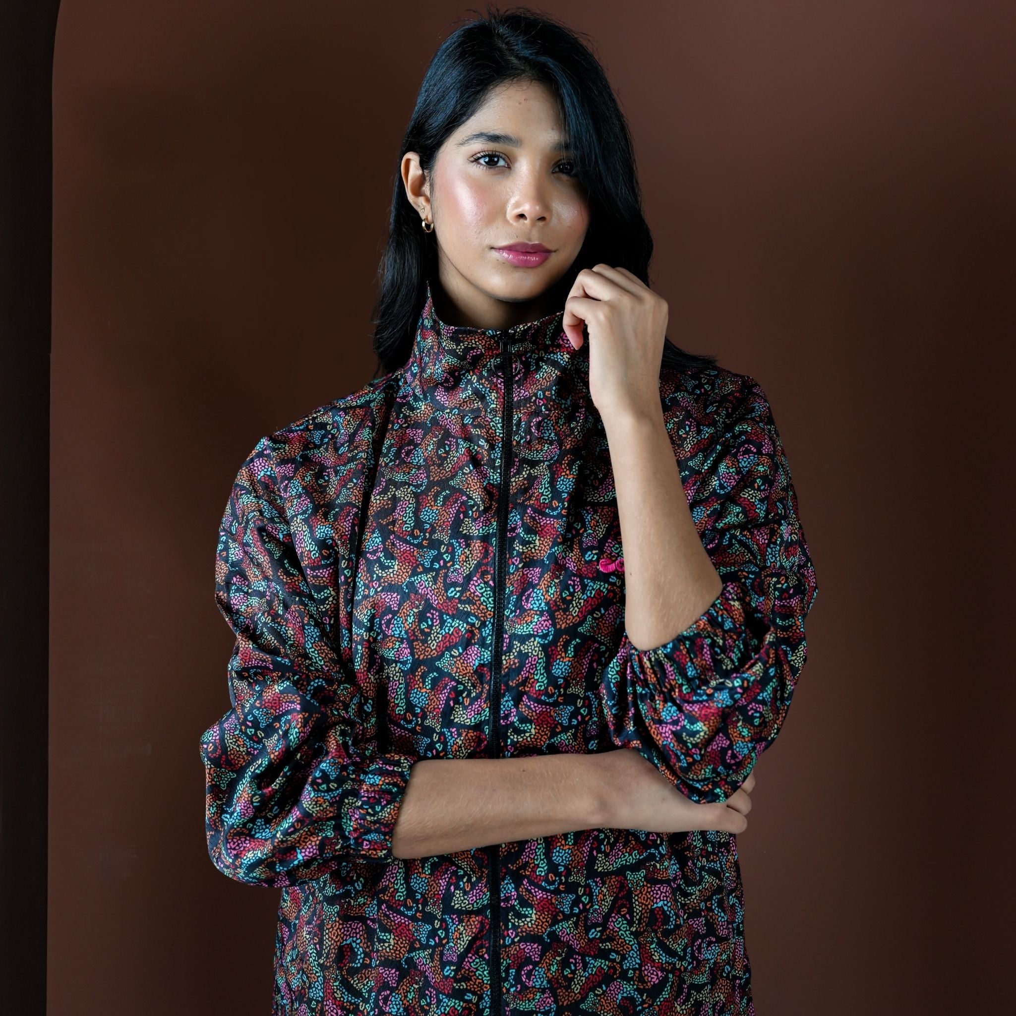 Woman wearing a colorful patterned outfit against a brown background