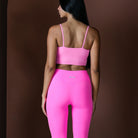 Person wearing a pink sports bra and leggings on a brown background