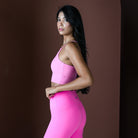 Woman wearing a pink athletic outfit against a brown background