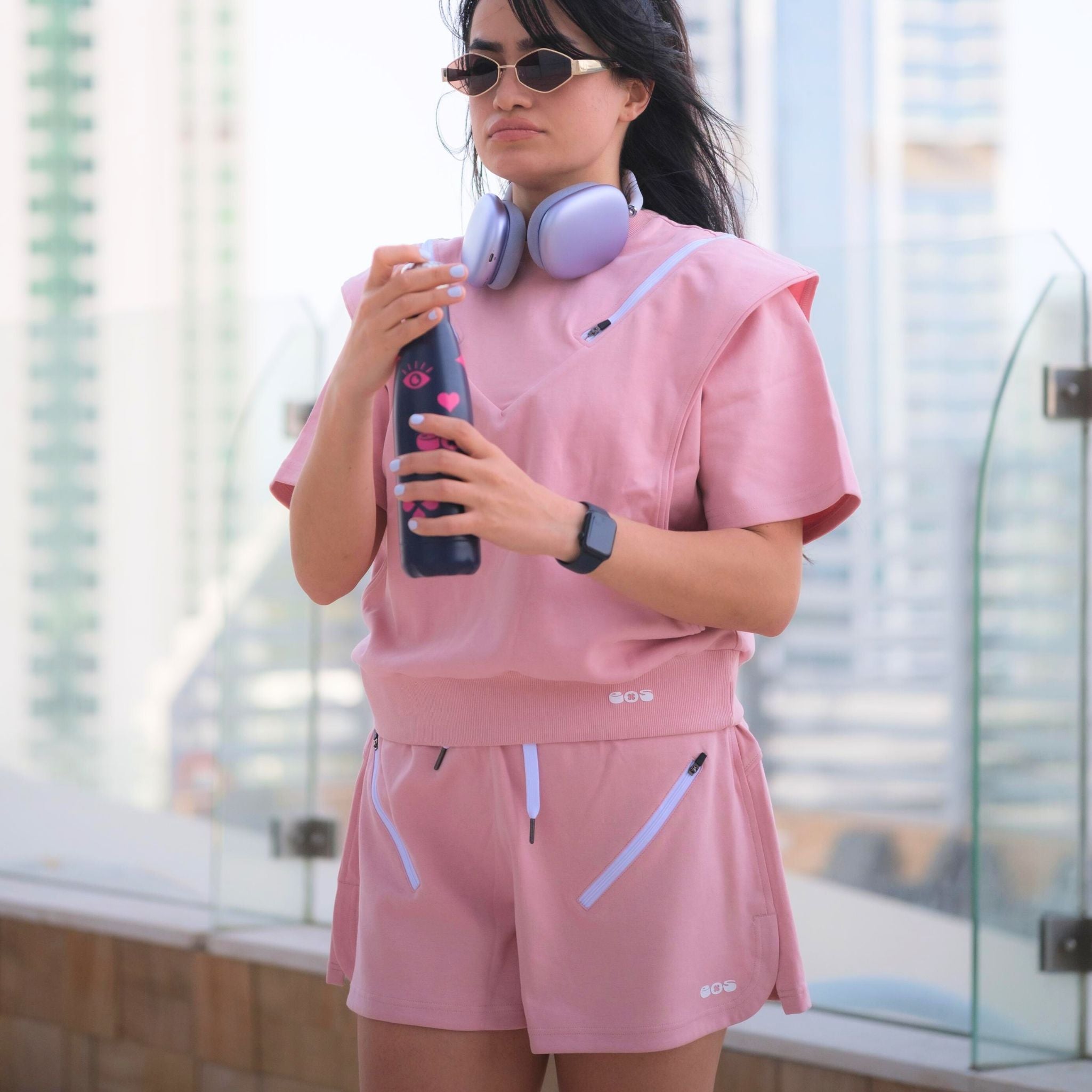 A person wearing pink double zip shorts with a matching top, standing outdoors.