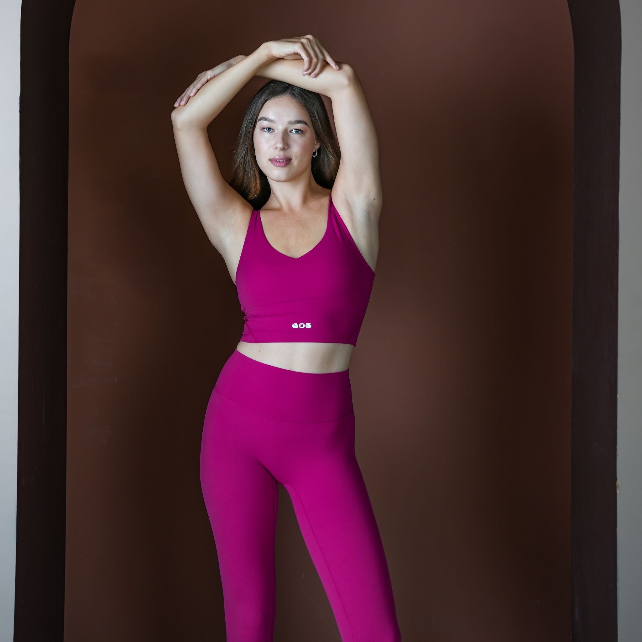 Woman wearing a bright pink athletic outfit against a brown background