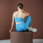 Woman in blue athletic wear sitting on a brown pedestal against a brown background