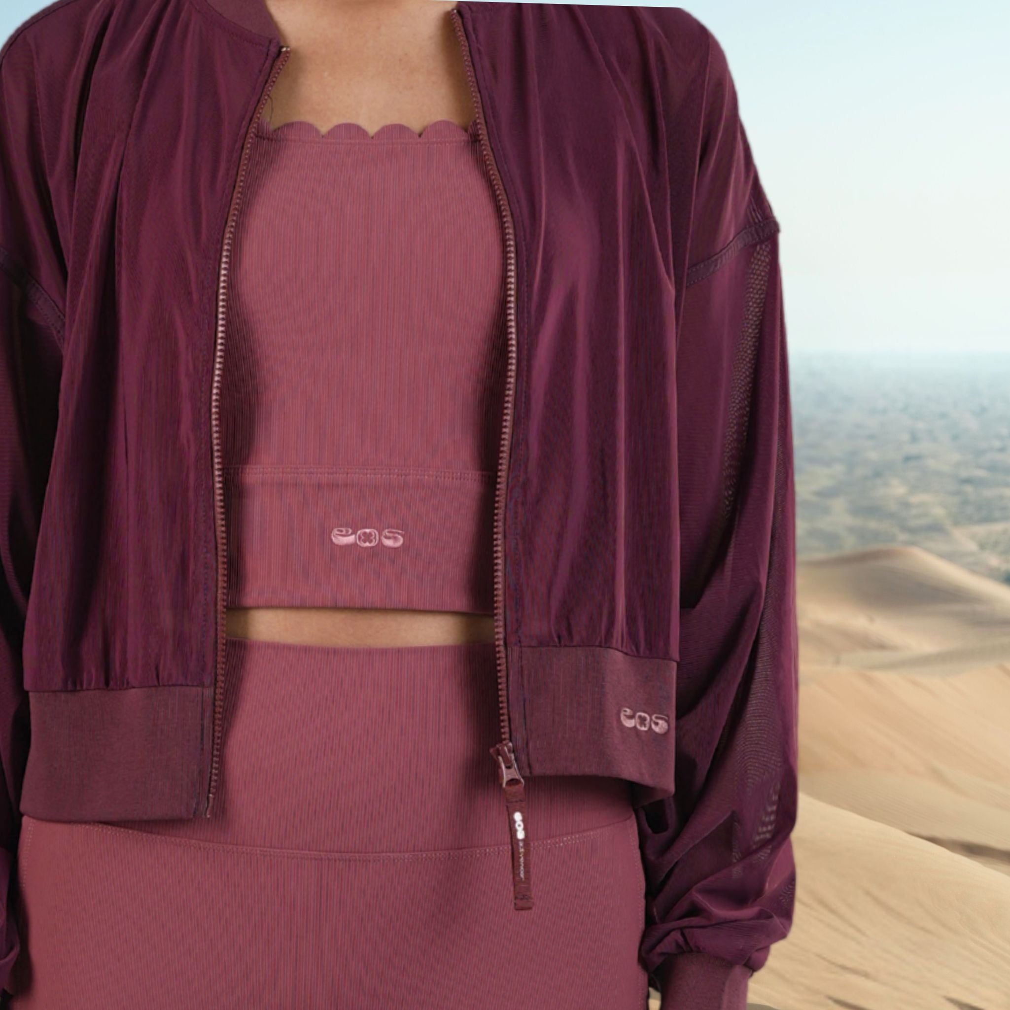 Maroon outfit with a jacket over a pink top and skirt, set against a desert landscape.