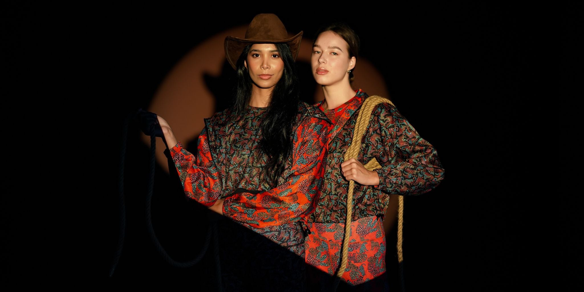 Two women in matching outfits with a dark background